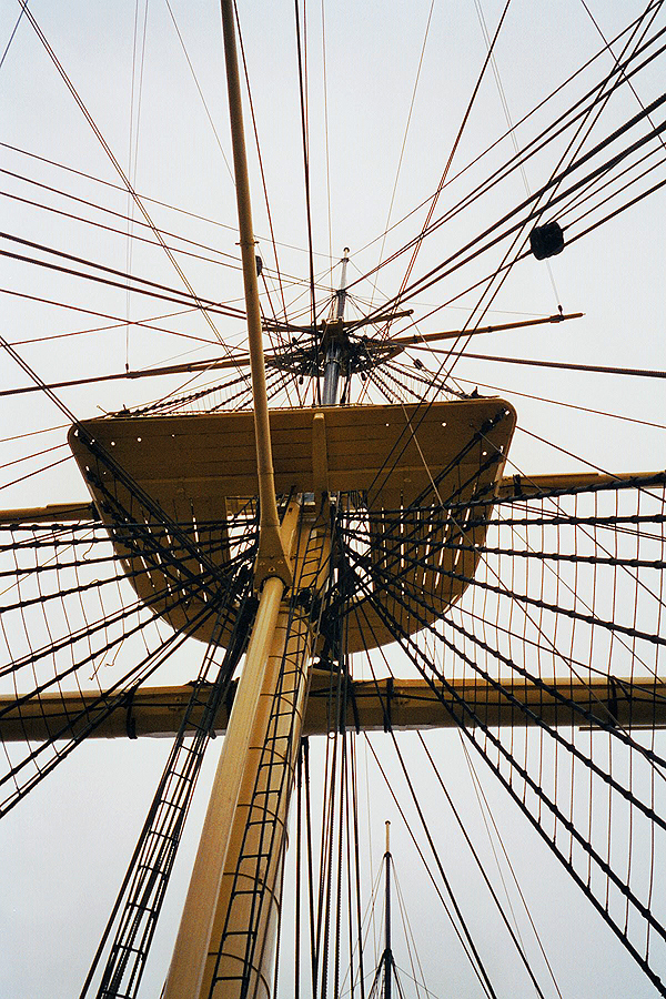 Mast of a sailing ship with the look-out and many thick and thin ropes which are tightend up in different directions.